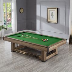 a pool table in the middle of a living room with hardwood floors and gray walls