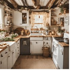 a rustic kitchen with white cabinets and wood flooring is decorated with greenery, pots and pans