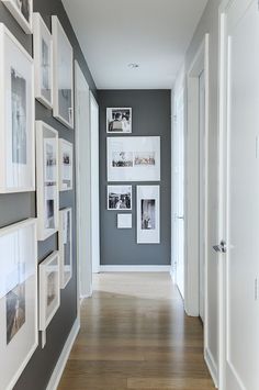 a long hallway with pictures on the wall and framed photos on the walls, along with hardwood flooring