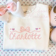 a pair of pink shoes sitting next to a white sweater with the word charlotte on it