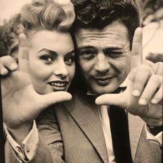 a man and woman posing for the camera with their fingers in the shape of v