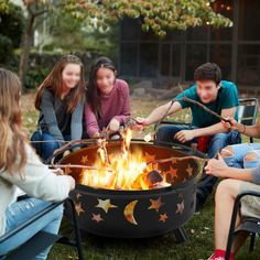 four people sitting around a fire pit in the grass