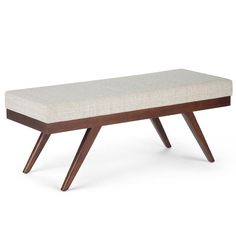 an upholstered bench with wooden legs and a light colored fabric seat pad on top