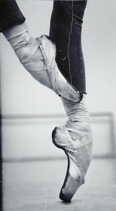 a ballerina's feet are shown in this black and white photo, while the bottom part of her leg is visible