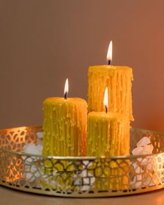 three yellow candles sitting on top of a metal tray