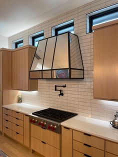 a kitchen with wooden cabinets and white tile backsplashes, an oven hood over the stove