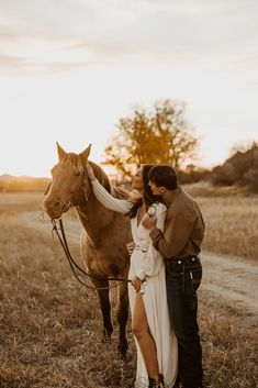 a man and woman standing next to a horse