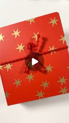 an open red gift box with gold stars on it and a string tied around the top