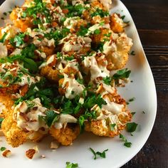 a white plate topped with cauliflower covered in sauce and garnished with parsley