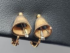 This little gold tone bell with silver tone clapper clip on earrings brings the holiday spirit. They  marked "Avon".  Measures 1/2" long.  I noticed very little sign of rusting  on one earring.  Perfect present for holiday season. Vintage Clip-on Hoop Earrings For Gift, Vintage Brass Clip-on Earrings Gift, Vintage Single Clip-on Earring In Metal, Vintage Clip-on Pearl Earrings As Gift, Vintage Gold Clip-on Earrings With Black Enamel, Avon Vintage, Christmas Bell, Vintage Avon, Christmas Bells