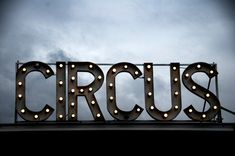 the word circus is lit up on top of a sign that says circus in lights