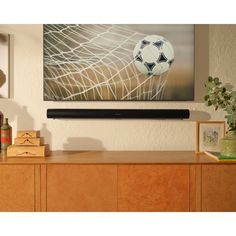 a painting hanging on the wall above a wooden cabinet with a soccer ball in it