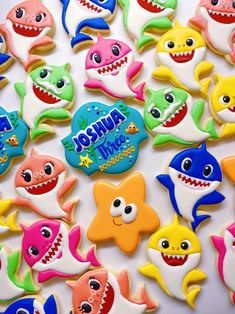 there are many decorated cookies that look like shark's on the table with other ones