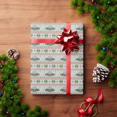 a wrapped present sitting on top of a wooden table next to pine cones and christmas decorations