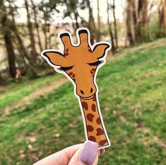 a person holding up a sticker with a giraffe face on it