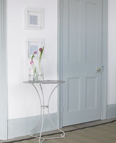 a white table with flowers on it in front of a blue door and carpeted floor