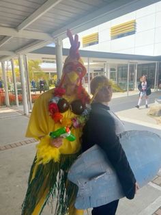 two people dressed up in costumes and carrying surfboards on the sidewalk at an outdoor mall