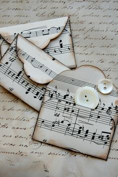 two pieces of paper with musical notes on them and buttons in the shape of envelopes