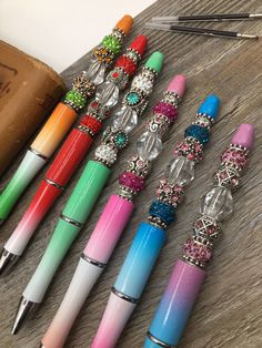 several different colored pens sitting on top of a wooden table