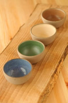 four small bowls are lined up on a wooden surface