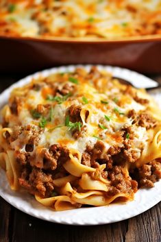 a white plate topped with lasagna next to a casserole dish on a wooden table