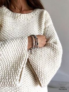 a woman wearing a white sweater and bracelets