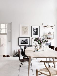 a dining room table with chairs and pictures on the wall above it, along with other furniture