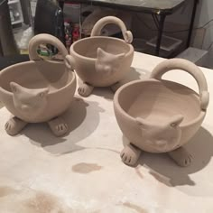 three clay bowls sitting on top of a table next to other pottery items in the shape of animals