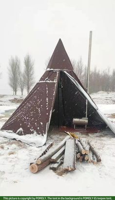 a teepee is covered with snow and logs