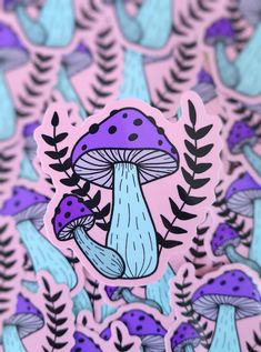 a purple and blue mushroom sticker sitting on top of a pile of green leaves