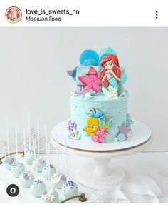 there is a blue cake with little mermaids on it and other sweets in the foreground