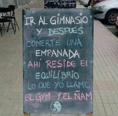 a chalkboard sign on the side of a sidewalk with writing in spanish and english