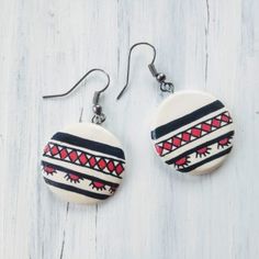 two white and red earrings on top of a wooden table