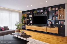 a living room filled with furniture and a flat screen tv sitting on top of a wooden shelf