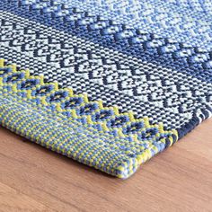 a blue and yellow rug on top of a wooden floor