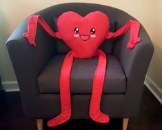 a stuffed heart sitting on top of a chair with a red ribbon around it's legs