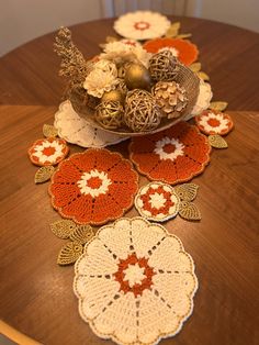 crocheted doily on top of a wooden table with an orange and white flower arrangement