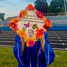 a person wearing a blue graduation gown holding up a sign that says no matter where life takes us you can find me with a smile