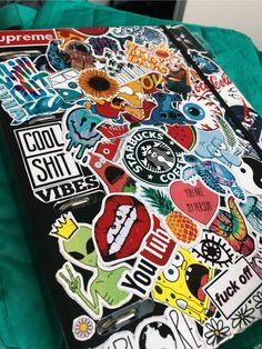 an assortment of stickers are on top of a green bag with the words supreme printed on it