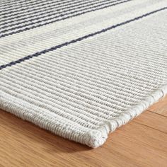 a close up view of a rug on the floor with wood floors and white fabric