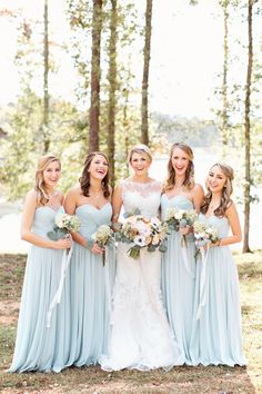 the bride and her bridesmaids pose for a photo in front of some trees