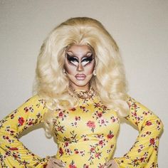 a woman with makeup on her face and long blonde hair wearing a yellow floral dress