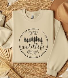 a sweatshirt with the words support wildlife raise boys on it next to some straws