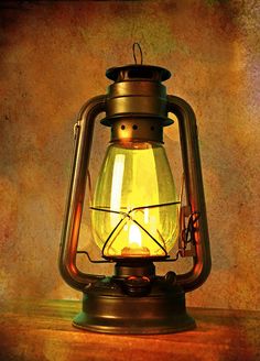 an old fashioned lantern with a candle inside on top of a wooden table in front of a grungy background