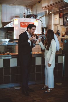 a man and woman standing next to each other in front of a food counter at a restaurant