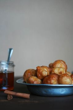 a bowl full of cinnamon rolls next to a jar of honey