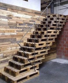 wooden stairs made out of pallets in front of a brick wall with metal handrails