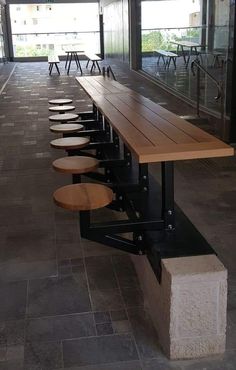 a long wooden table sitting in front of a glass wall with benches on each side