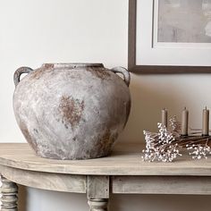 a vase sitting on top of a wooden table next to a candle holder and flowers