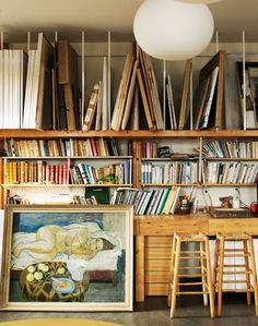 the bookshelves are full of books and there is a painting on the table